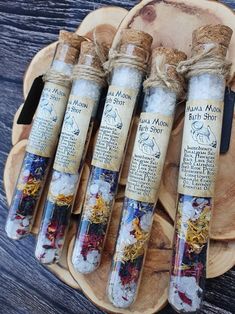 four glass bottles filled with sand and seaweed on top of a wooden tray next to a knife