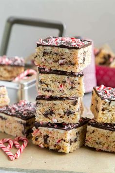 several pieces of cookie bars stacked on top of each other with candy canes in the background