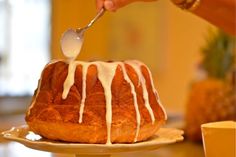 a person drizzling icing onto a bundt cake on a plate