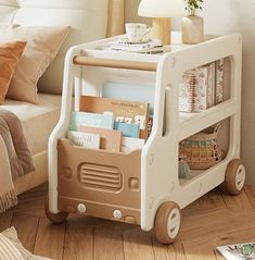 a toy bus with books and magazines in it on the floor next to a bed