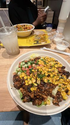 a white plate topped with meat and vegetables next to a drink on a wooden table