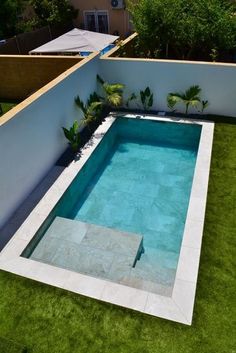 an empty swimming pool in the middle of a backyard with green grass and trees around it