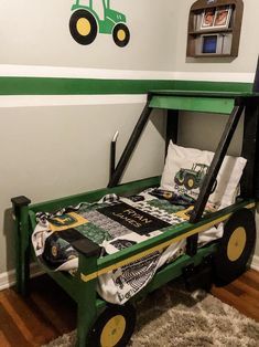 a child's bed made to look like a tractor with green tires and wheels