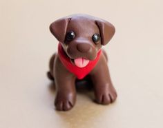 a small brown dog with a red heart on it's collar sitting on a table