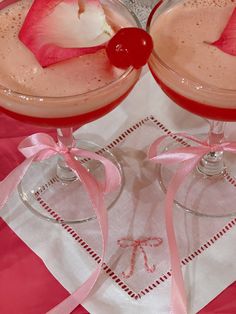 two martinis with pink ribbons and cherries on them