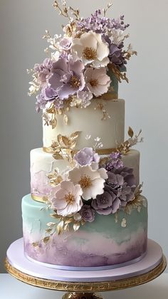 there is a multi layer cake with flowers on the top and bottom, decorated in pastel colors