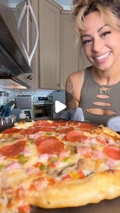 a woman is smiling while looking at a pizza