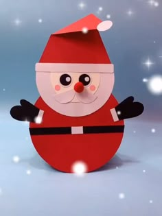 a paper santa clause standing in the snow with his arms out and eyes wide open