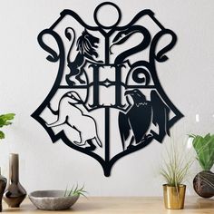 a metal hogwarts crest on a wall next to potted plants and vases