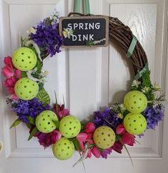 a wreath with bowling balls and flowers hanging on the front door for springtime fun