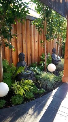 a small garden with buddha statues and plants in the center, surrounded by wooden fence