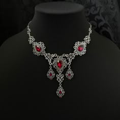 "This romantic necklace features richly detailed antiqued silver filigrees, scrolls and beaded accents. Adorned with sparkling dark ruby red glass crystals, its breath taking design will add Victorian elegance to your outfits. Decorated portion is 8 1/4\" wide and 2 3/4\" tall in the very center.  Necklace length is adjustable with soldered stainless steel cable chain, lobster clasp and extender. If you would like a different length, please send us a message. Matching headpiece and earrings are listed separately in our store. If you don't see items with a color you want, feel free to ask about availability." Red Metal Filigree Jewelry, Gothic Metal Necklace With Intricate Design, Gothic Wedding Necklace With Filigree Detail, Gothic Filigree Necklace For Wedding, Gothic Filigree Wedding Necklace, Ornate Red Wedding Necklaces, Ornate Red Filigree Necklaces, Ornate Red Filigree Necklace, Fantasy Jewellery