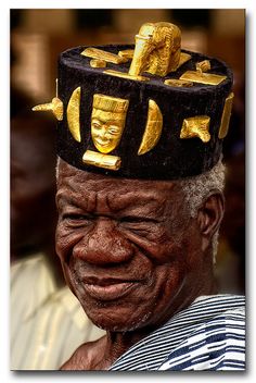 an older man wearing a black and gold hat