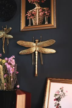 there are two framed pictures on the wall with dragonflys and flowers in vases