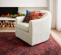 a white chair sitting in front of a fire place with pillows on top of it