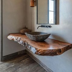 a bowl shaped sink sitting on top of a wooden counter next to a wall mounted mirror