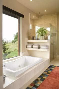 a bathroom with a large bathtub next to a window and a rug on the floor