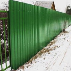 a green metal fence with snow on the ground