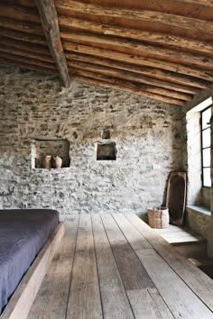 a bedroom with stone walls and wooden floors