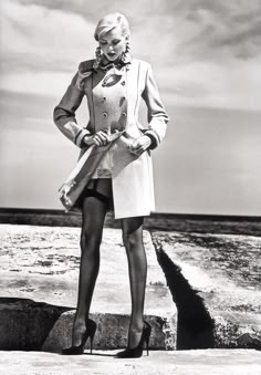 a woman is standing on the beach with her hands on her hips and wearing high heels