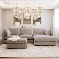 a living room with a couch, ottoman and chandelier