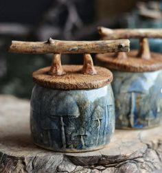 two ceramic containers sitting on top of a wooden table next to another container with wood handles