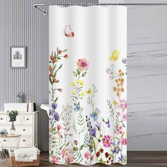 a shower curtain with colorful flowers and butterflies on it in a bathroom next to a white dresser