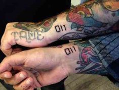 two people with tattoos on their arms holding each other's hands and one has the word