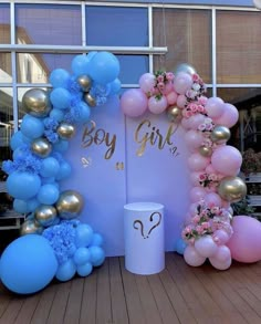 there is a balloon arch with flowers and balloons around it that says boy girl on the side