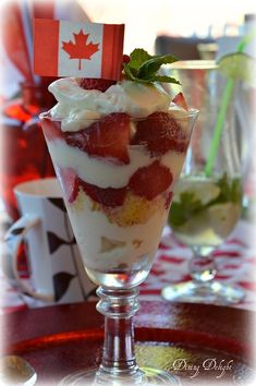 a dessert with strawberries and whipped cream in a glass on a red tablecloth