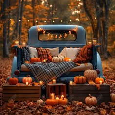 an old truck with pumpkins and candles in the bed is surrounded by fall leaves