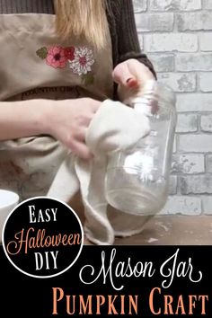 a woman in an apron is making pumpkin craft with mason jar and paper napkins