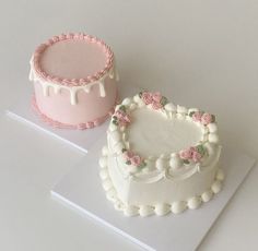 two decorated cakes sitting on top of a white table next to each other, one with pink frosting