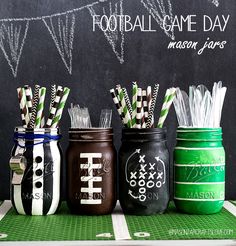 four mason jars with straws in them on a green tablecloth next to a chalkboard