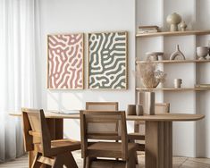 a table and chairs in a room with two paintings on the wall