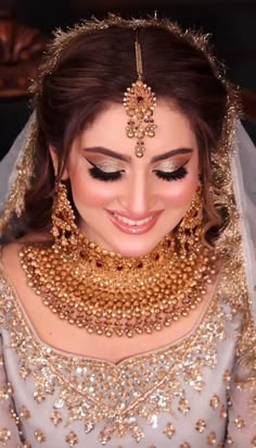 a woman in a bridal outfit with gold jewelry on her neck and headpiece