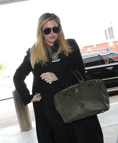 a woman carrying a green handbag while standing in an airport