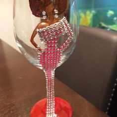 a wine glass with an image of a woman on the bottom and beads around it