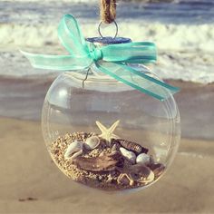 a glass ornament filled with sand and sea shells