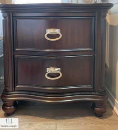 a wooden dresser with two drawers and gold handles