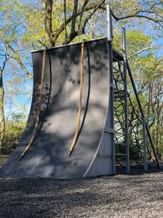 a large metal slide in the middle of a park with lots of trees behind it