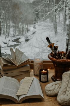 an open book sitting on top of a window sill next to candles and books