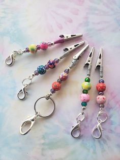 five different colored beads and metal scissors on a table