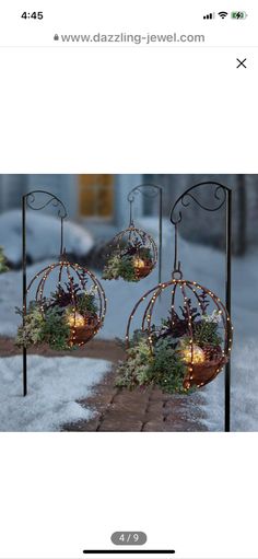 two metal planters with lights hanging from them in the middle of snow covered ground