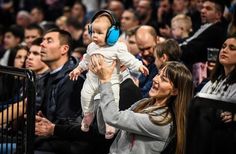 a woman holding a baby wearing headphones while sitting in front of a group of people