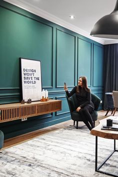 a woman sitting in a chair with a poster on the wall next to her,