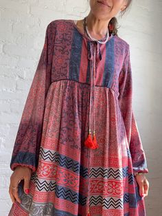 "This is very cute and beautiful light silky tunic dress with floral print in delicate grey and pink colours true boho chic style it is made loose and flared with high waist and long puff sleeve  effortles to wear and easy fitting to all shapes perfect outfit for many occasions parties dinners birthday, great maternity outfit 😊 MEAESURE size M/L shoulders 17\" bust up to 37\" ( it is front tie srap, so can be easyli loosen up or tighten ) high waist 36\" length 40\" MATERIAL *mixed silk, no lin Spring Maxi Dress With Back Tassel Tie-up, Billowy Long Sleeve Floral Print Dress, Spring Boho Maxi Dress With Back Tassel Tie-up, Bohemian Non-stretch Long Maxi Dress, Modest Flowy Rayon Dress, Long Bohemian Dress With Back Tassel Tie-up, Feminine Flowy Dress With Elastic Neckline, Bohemian Non-stretch Floral Print Dress, Summer Viscose Tunic Dress