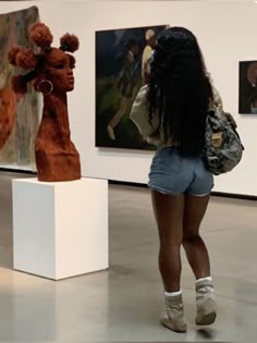 a woman is looking at sculptures in an art gallery with her back to the camera