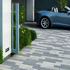 a blue sports car is parked in front of a house with an open garage door