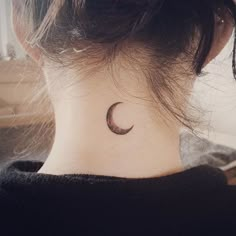 a woman's neck with a small crescent tattoo on the back of her neck